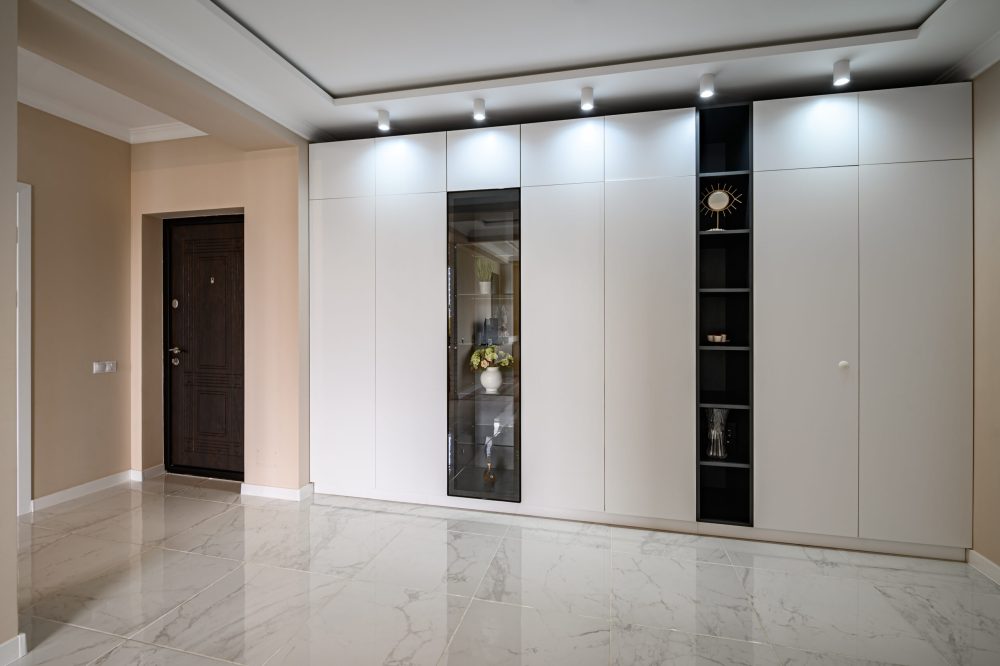 Empty hallway of modern studio apartment with white kitchen and beige bedroom